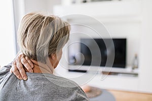 Senior woman in living room with neck pain