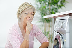 Senior woman loading washing machine at home