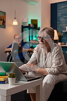 Senior woman looking at laptop on sofa at home