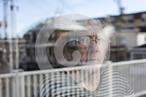 Senior woman looking out through a window like depress