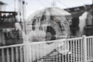 Senior woman looking out through a window like depress