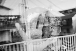 Senior woman looking out through a window like depress