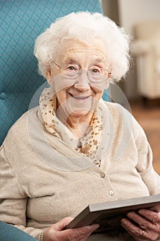 Senior Woman Looking At Photograph In Frame