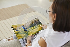 Senior woman looking through photographs in her family photo album or memory book