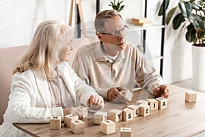 senior woman looking at sick husband near wooden cubes with dyslexia letters.