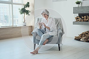 Senior woman looking at smartphone screen watching funny photo or video