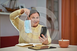 Senior woman looking at smartphone showing blue mask