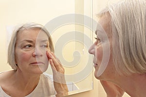 Senior woman looking wrinkles mirror