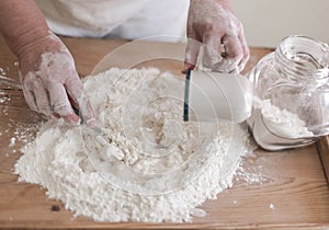 Senior woman makes pastry by mixing flour and water