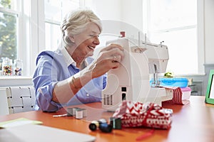 Senior Woman Making Clothes Using Sewing Machine At Home