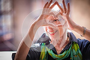 Senior woman making a heart shape, cute and lovely
