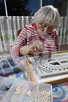Senior woman making a necklace