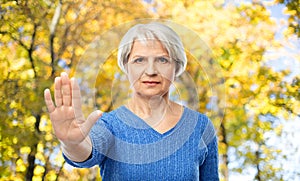 Senior woman making stop gesture in autumn park