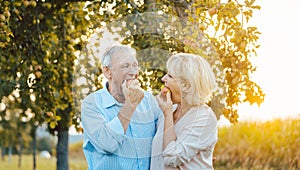Senior woman and man enjoying an apple in late summer sunset