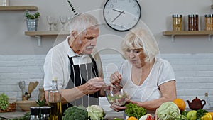 Senior woman and man feeding each other with fresh raw vegetable salad. Eco food eating diet
