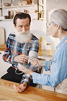 Senior woman and man at home meassure blood pressure