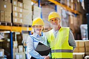 Senior woman manager and man worker standing in a warehouse.