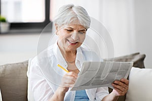 Senior woman marking newspaper ad at home