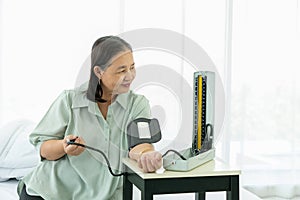 Senior woman measures blood pressure on her left hand with a digital blood pressure monitor