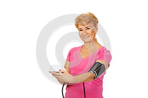 Senior woman measuring blood pressure with automatic manometer