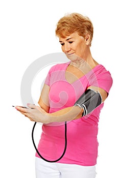 Senior woman measuring blood pressure with automatic manometer