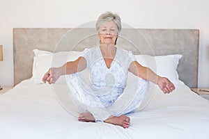 Senior woman meditating in bed