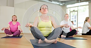 Senior woman meditating at group yoga class