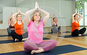 Senior woman meditating at group yoga class