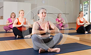 Senior woman meditating at group yoga class