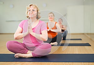 Senior woman meditating at group yoga class