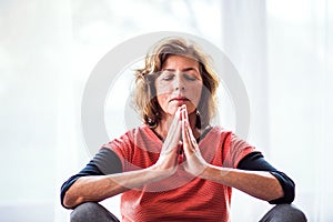 Senior woman meditating at home.