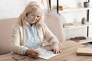 senior woman with mental illness drawing on paper.