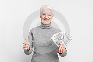 Senior woman with money giving thumbs up