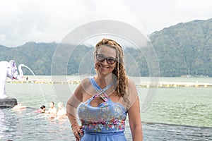Senior woman near the nature swimming pool with amazing mountain background. Tropical island Bali, Indonesia.