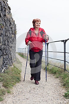 Senior woman Nordic walking on rocky trail