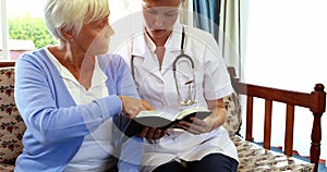 Senior woman and nurse reading a book together