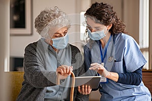 Senior woman and nurse using digital tablet at home during consult