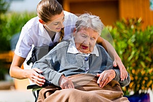 Senior woman in nursing home with nurse in garden