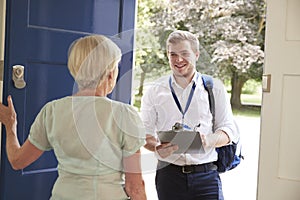 Senior woman opens door to male charity worker doing survey