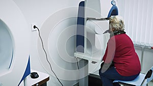 Senior woman at ophthalmologist cabinet doing vision test with modern equipment
