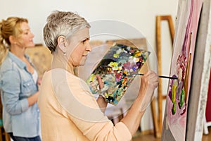 Senior woman painting at art school studio