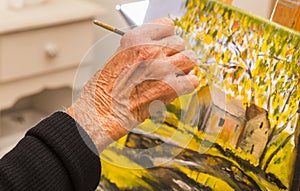 Senior woman painting, closeup of hand holding brush