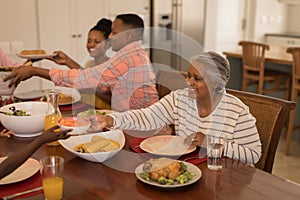 Senior woman passing food to her grandson on dinning table