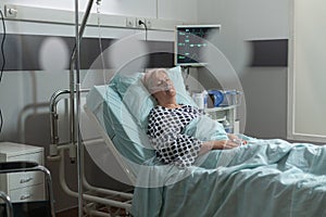 Senior woman patient in hospital room getting medicine through intravenous line