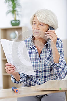 Senior woman on phone assembling furniture