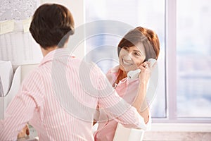 Senior woman on phone call, sitting with coworker photo