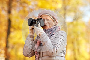 Senior woman with photo camera at autumn park