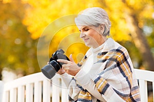 Senior woman with photo camera at autumn park