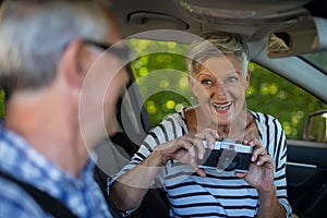 Senior woman photographing man in car