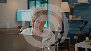 Senior woman with physical disability looking at laptop screen